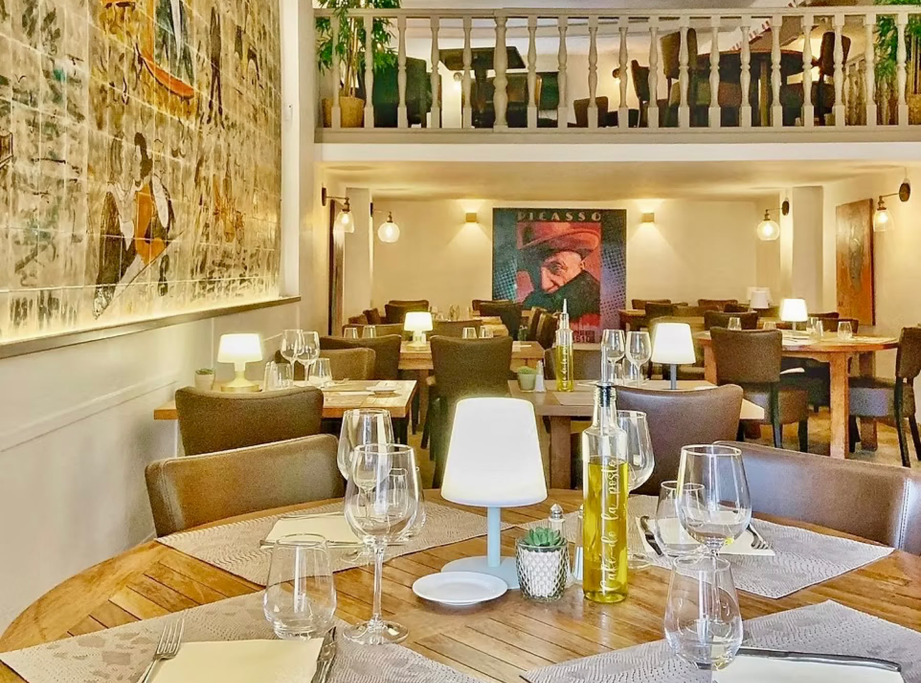 Le Café de la Poste, located in the heart of the village of Biot, has been a true local institution since 1885. With its period façade, shaded terrace under the plane trees by the fountain, and cozy interior featuring a mezzanine, faience mural, painted beams, and colorful chandelier, it offers a warm and authentic atmosphere. It’s a must-stop for anyone looking for a typical Provençal bistro, with a charming setting and quality Mediterranean cuisine at truly reasonable prices.